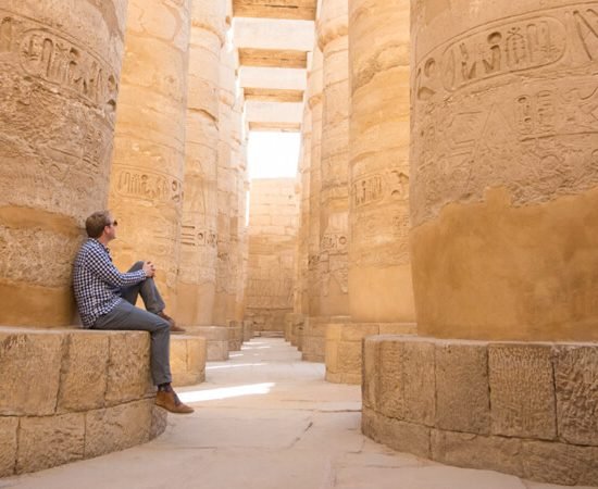 Visitor resting among ancient columns in luxor