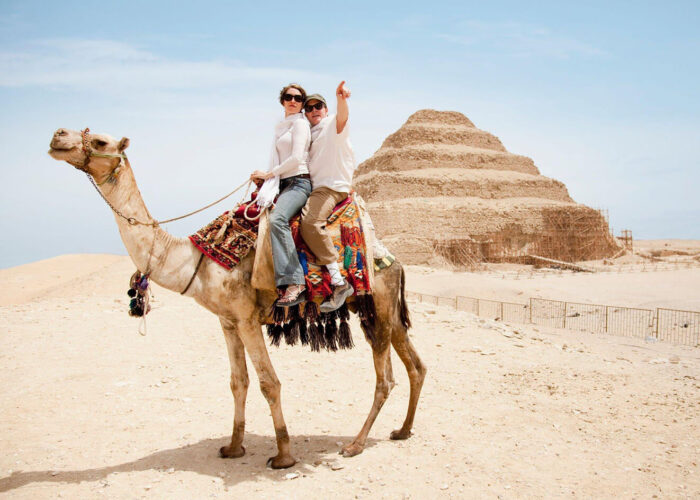 Camel riders near ancient pyramid.